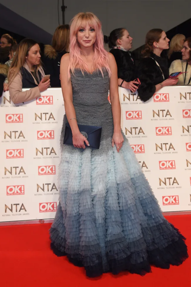 A woman with pink hair in a ruffled ombre gown on the red carpet at the National Television Awards.