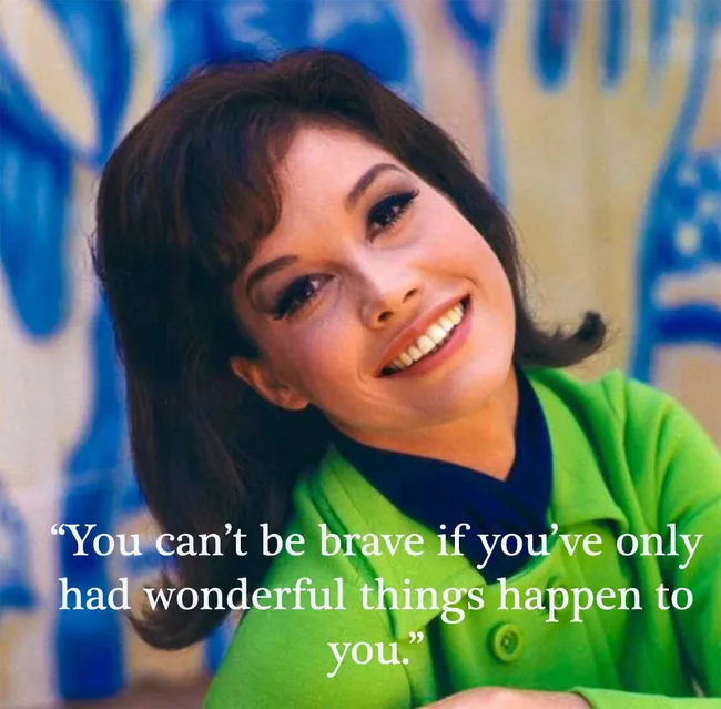 Smiling woman in green jacket with motivational quote: "You can&rsquo;t be brave if you&rsquo;ve only had wonderful things happen to you."
