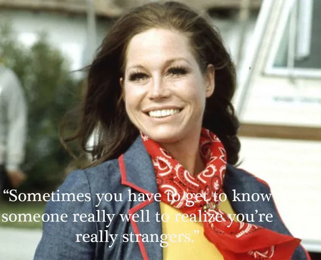 ```plaintext
Woman smiling in a blue jacket with red bandana, outdoor setting, with quote about knowing someone and being strangers.
```
