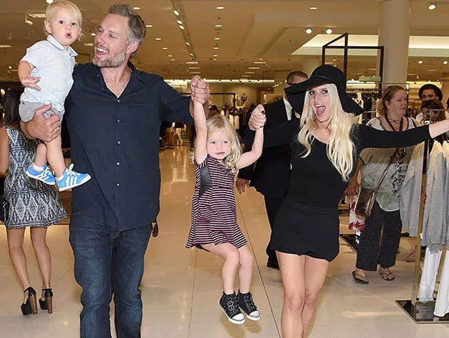 Family enjoying a day out, with parents swinging two young children in a shopping mall.
