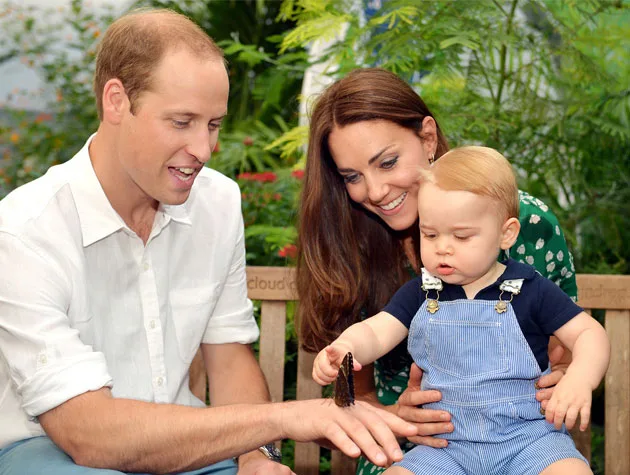 A family with a young child sitting on a bench, admiring a butterfly on the father's hand, surrounded by greenery.