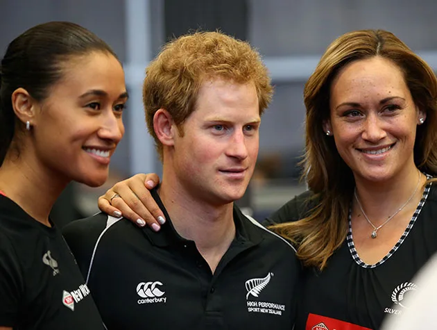 Three people smiling, with two women standing on either side of a man in a black shirt, posing together.