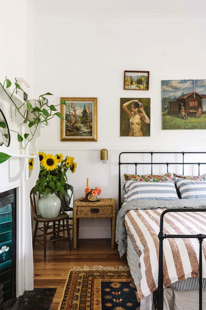 A country bedroom with striped bedding and a vase of sunflowers