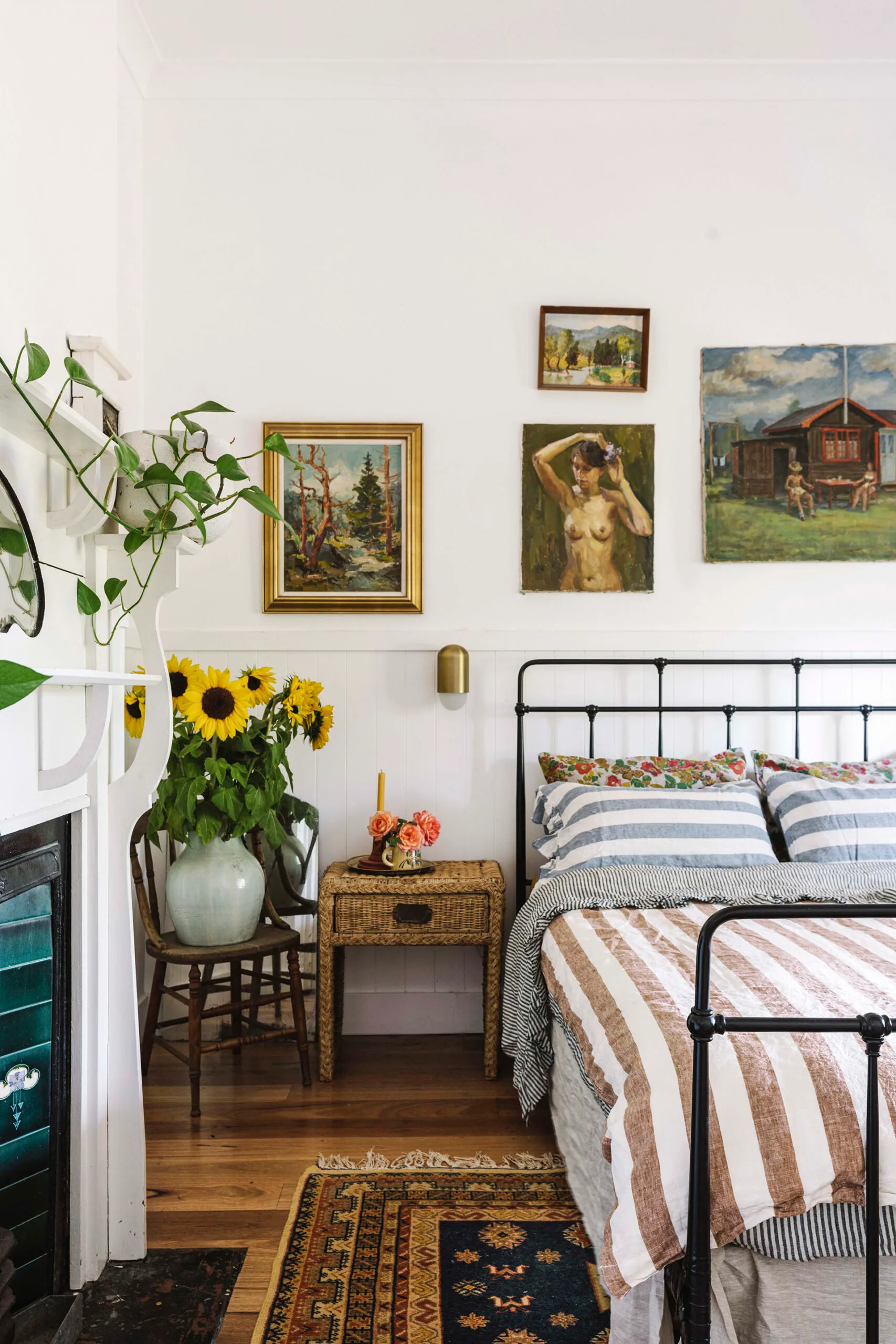 A country bedroom with striped bedding and a vase of sunflowers