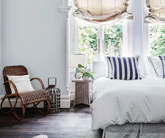 A modern country bedroom with white sheets and a big window.