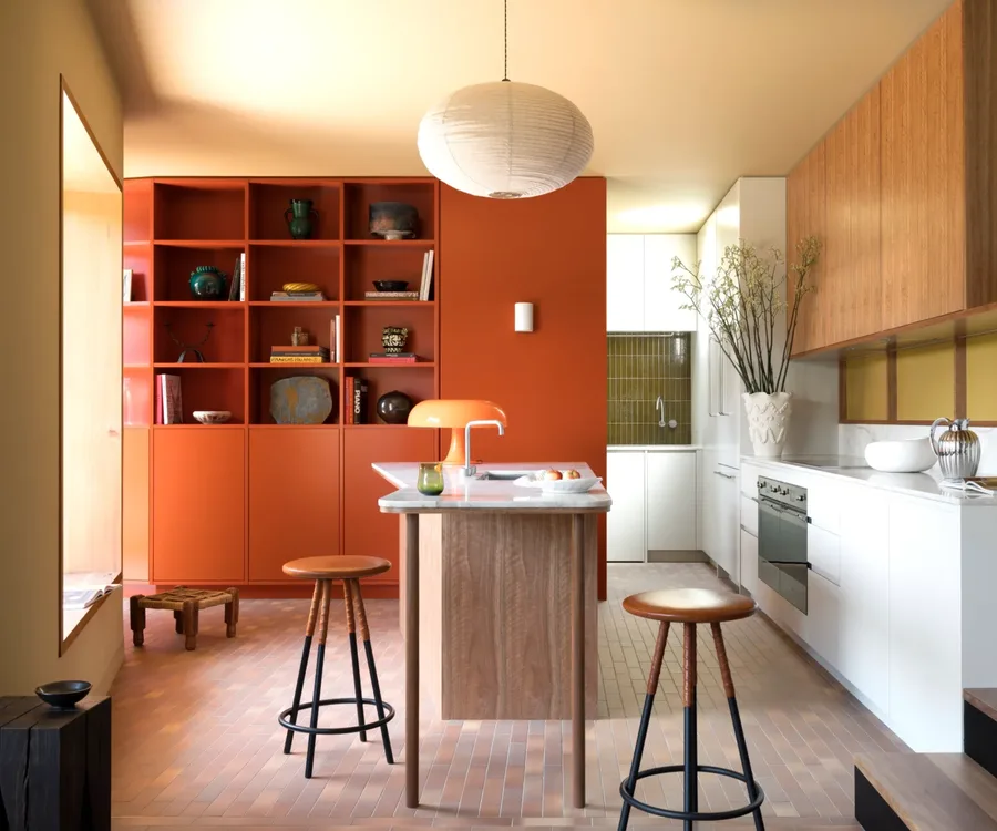 A retro-style kitchen with orange cabinetry and green splashbacks