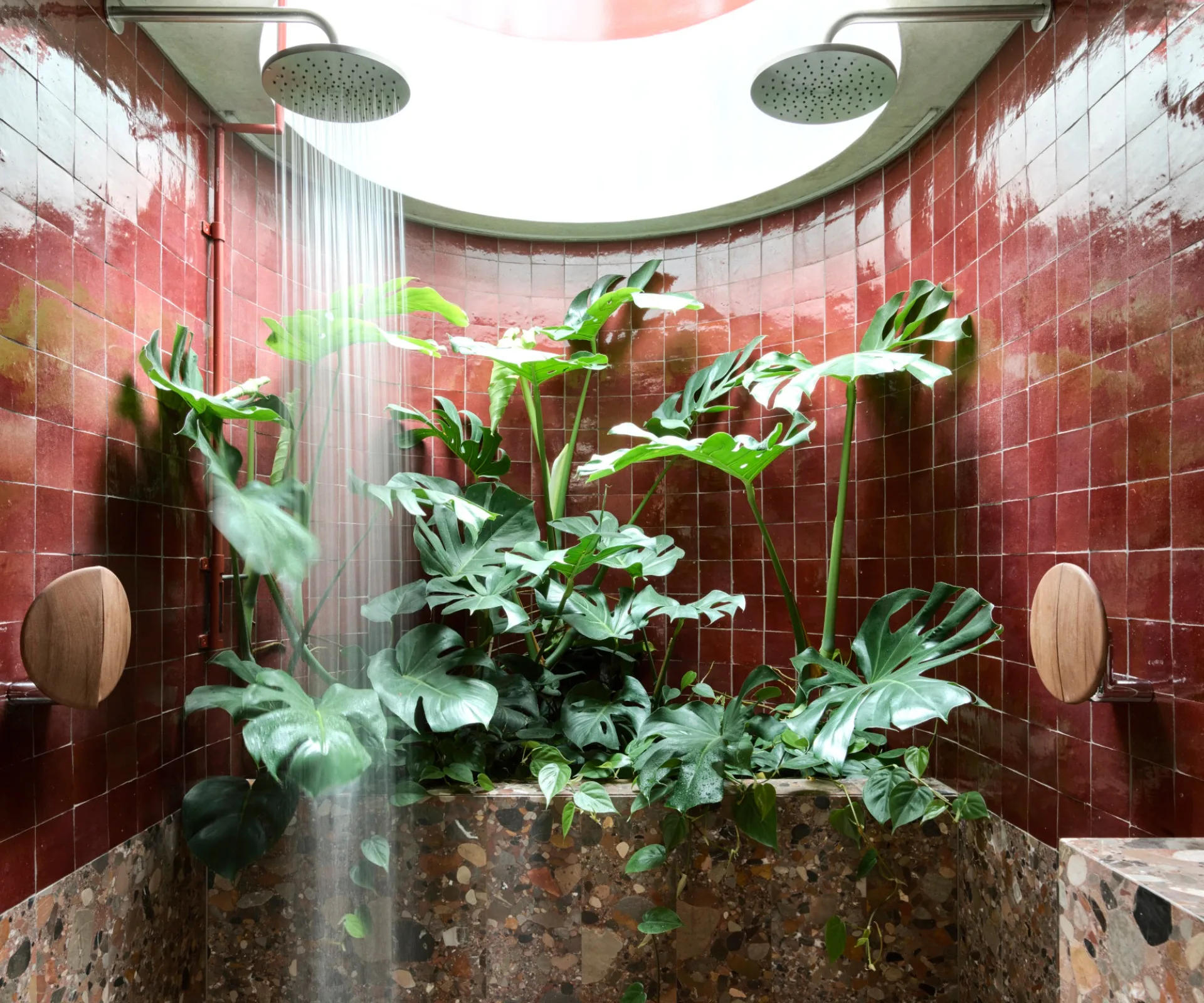 A bold double shower with red tiles, marble and a skylight