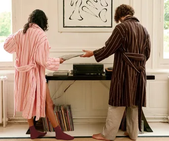 Two people playing vinyl wearing Hommey robes