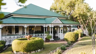 A Queenslander home with a white lattice verandah and a mint green roof