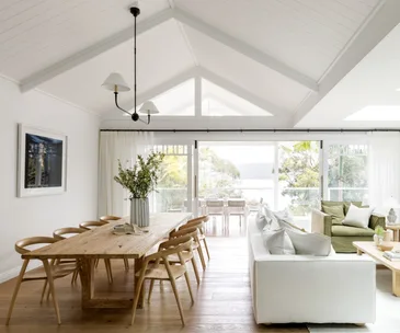 Bright and white interiors of an open-plan living and dining area in a renovated weatherboard