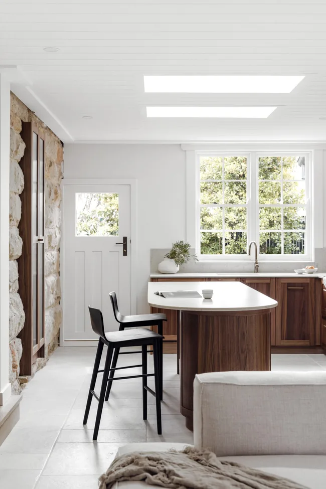 A modern kitchen with a sandstone feature wall and dark timber cabinetry