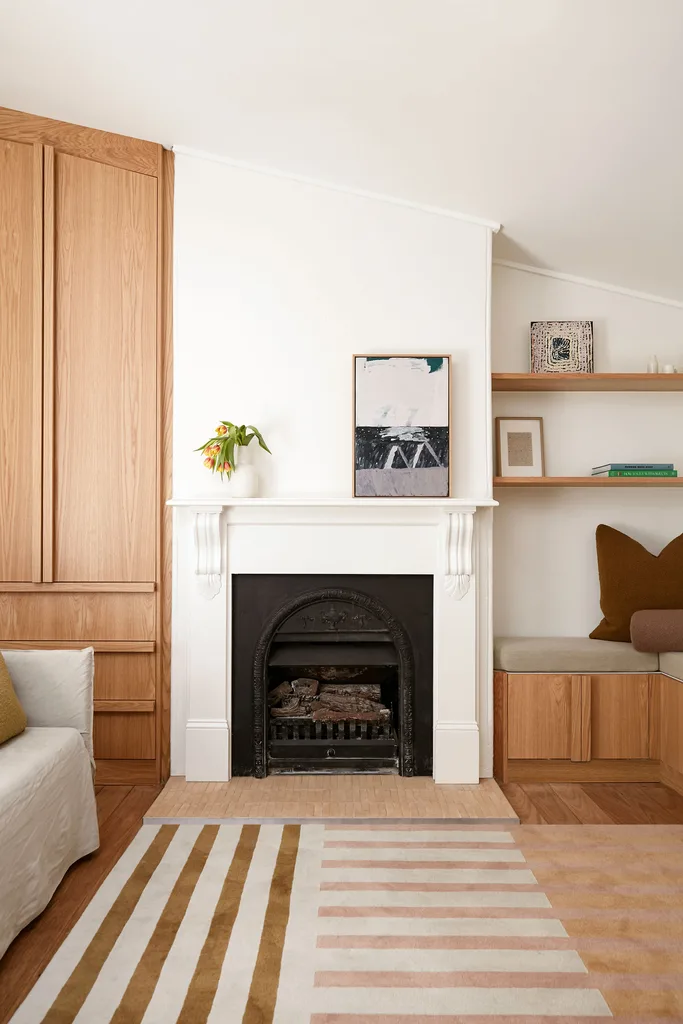 original fireplace in living area with a striped rug and timber joinery