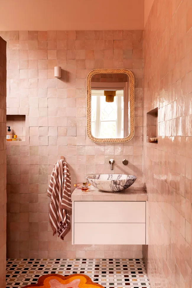 A pink-tiled bathroom with a floating vanity and striped hand towel