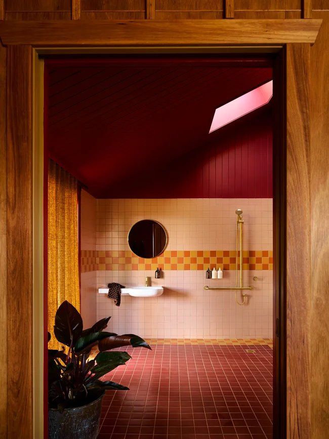 A stylish pink and red bathroom with a circular mirror