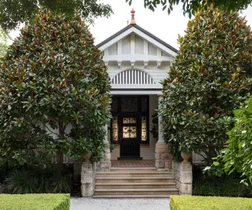 traditional home with stone front steps surrounded by large shade trees