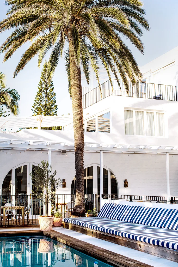 A pool area with striped loungers and a palm tree at Halcyon House