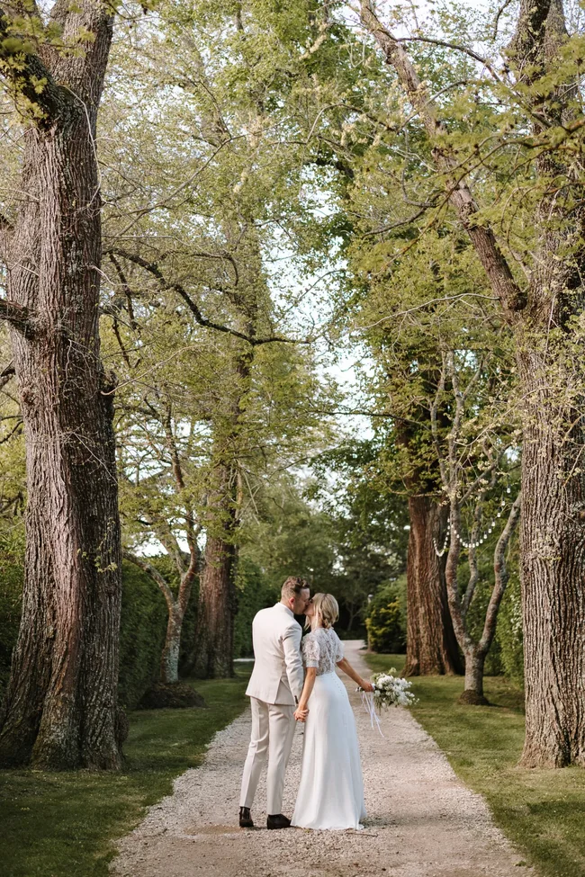 A couple kissing on their wedding day surrounded by trees
