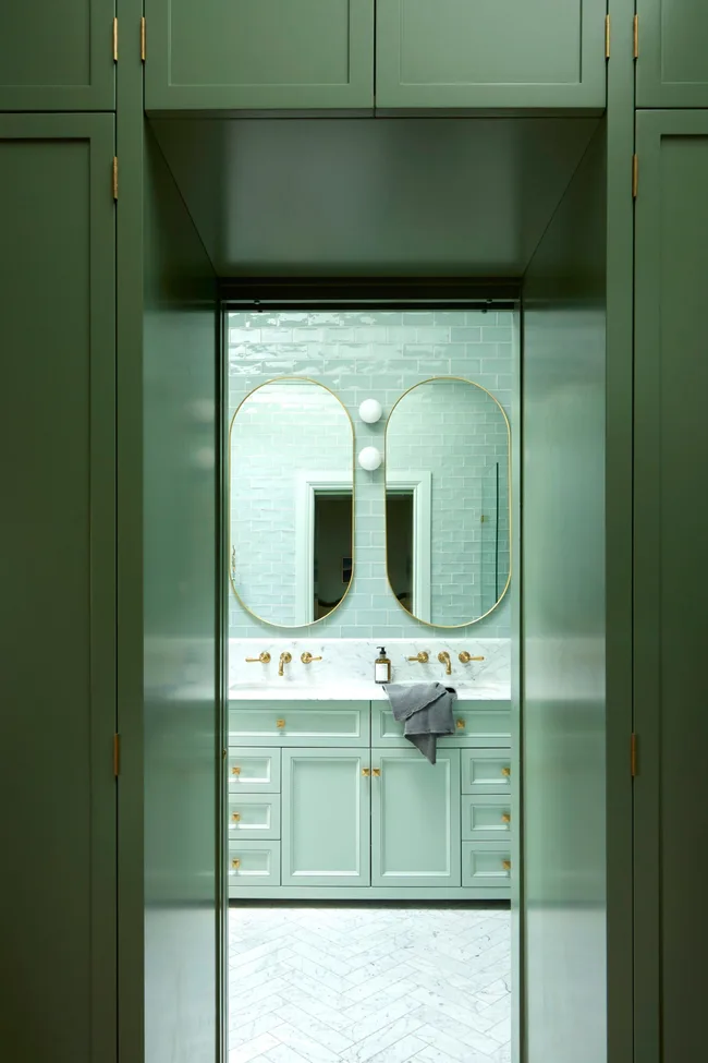 A mint green ensuite with a double vanity and green shaker-style cabinetry