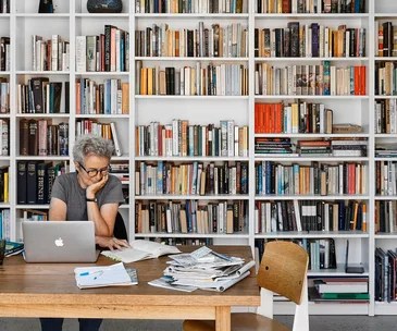 A woman reading a book in a white-washed contemporary-style home library