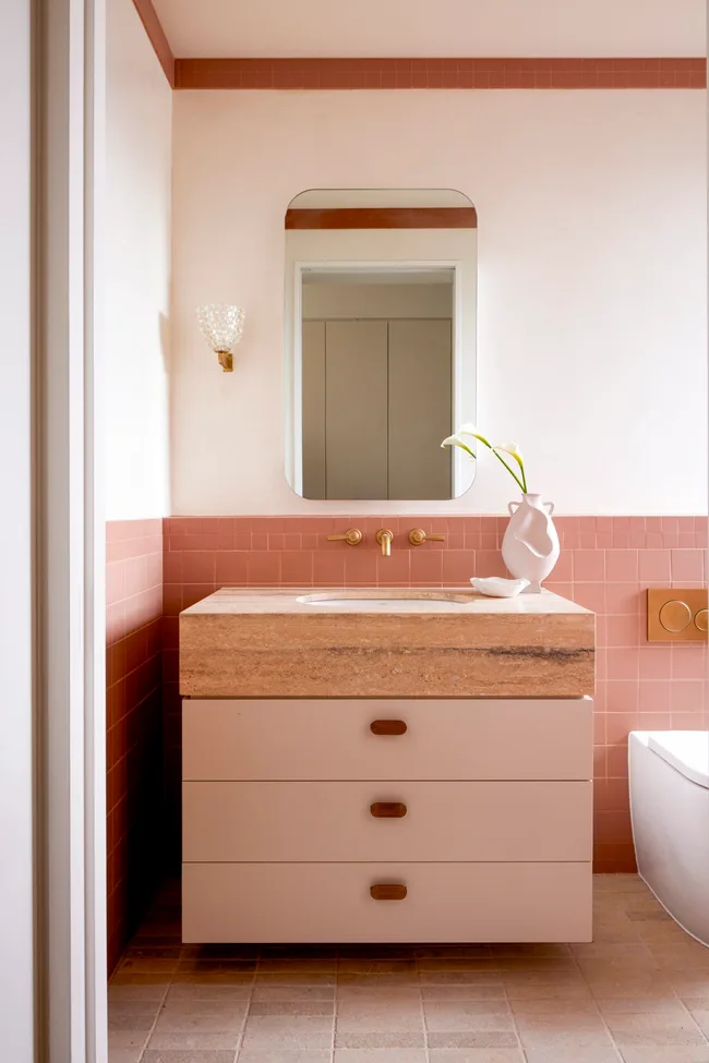 A pink bathroom with a pink vanity