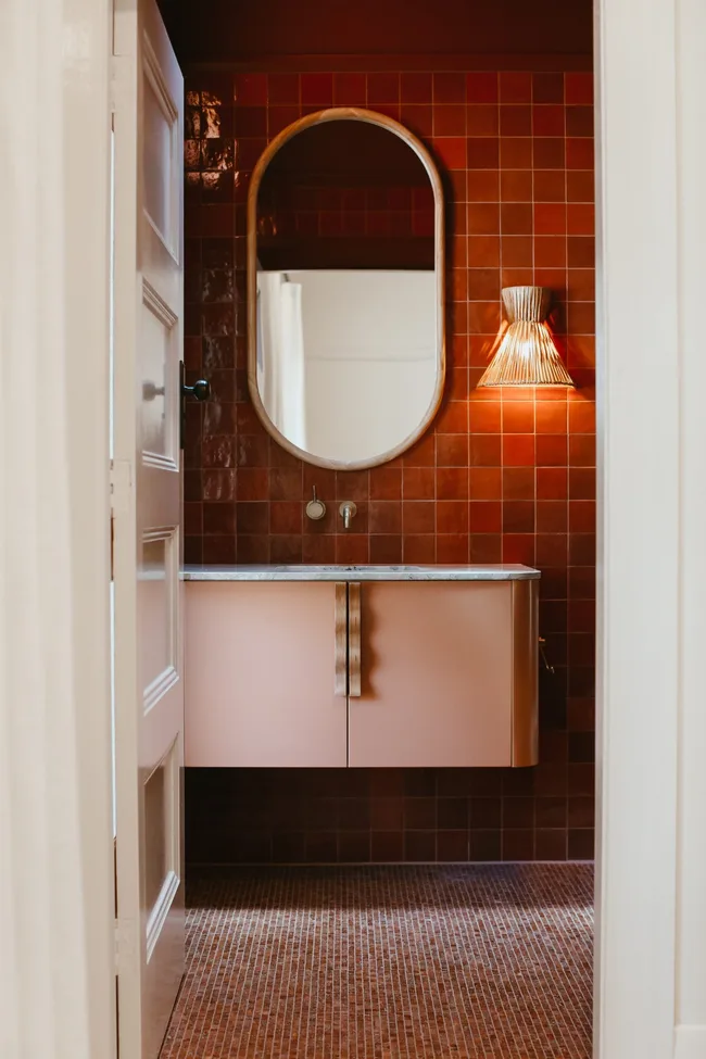 A pink and red bathroom with a floating vanity