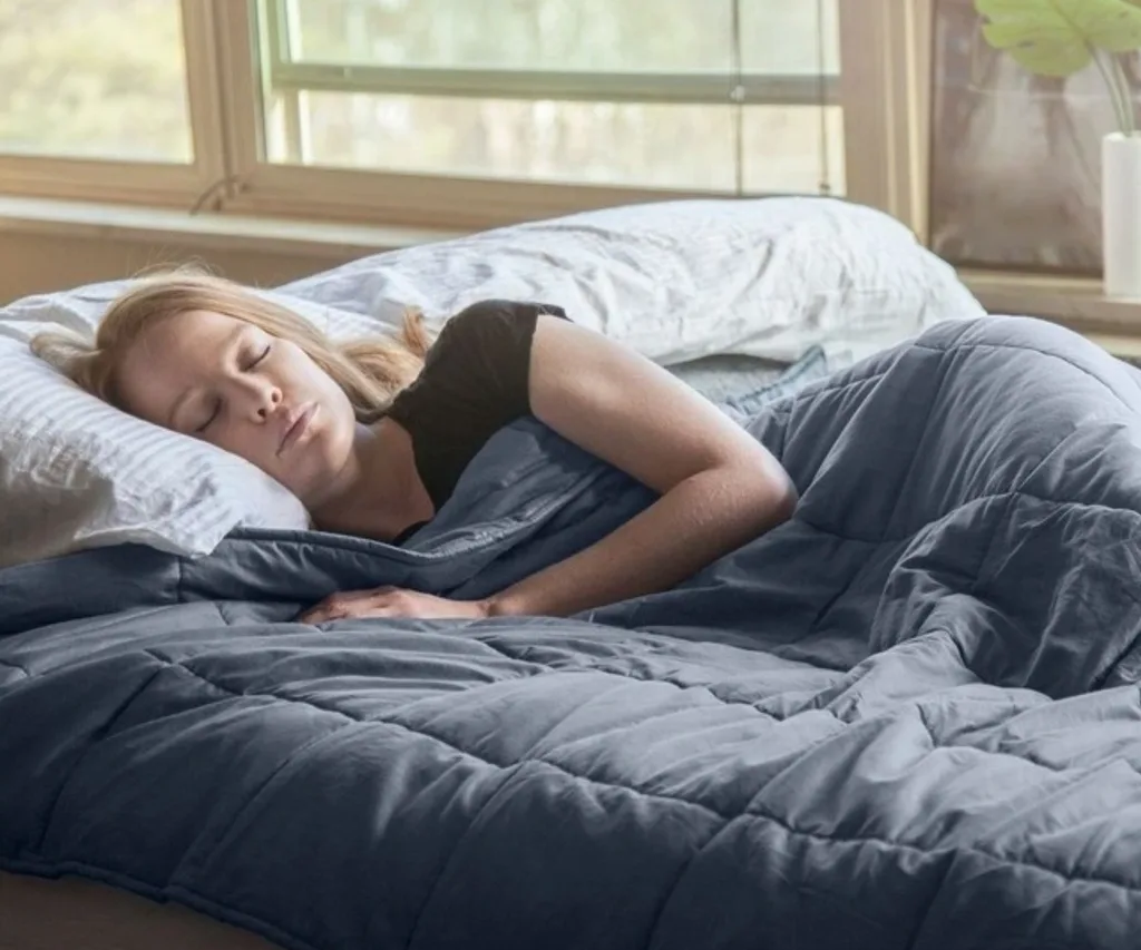 A woman sleeping on a bed with a weighted blanket