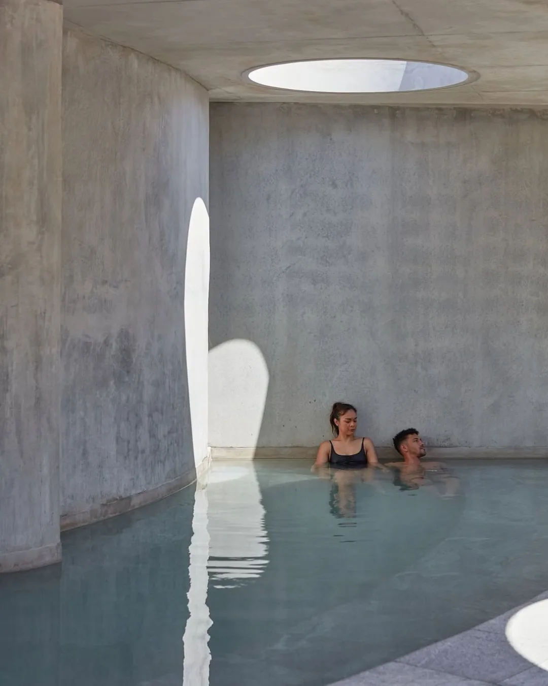 A concrete bath with people sitting in bath 