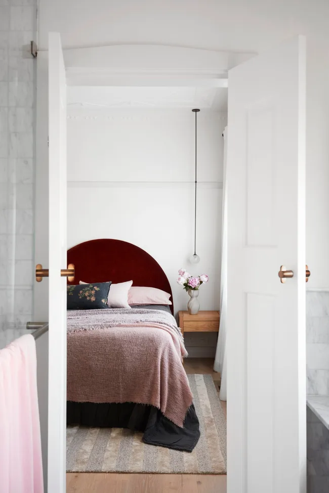 A white bedroom with pops of burgundy, pink and charcoal