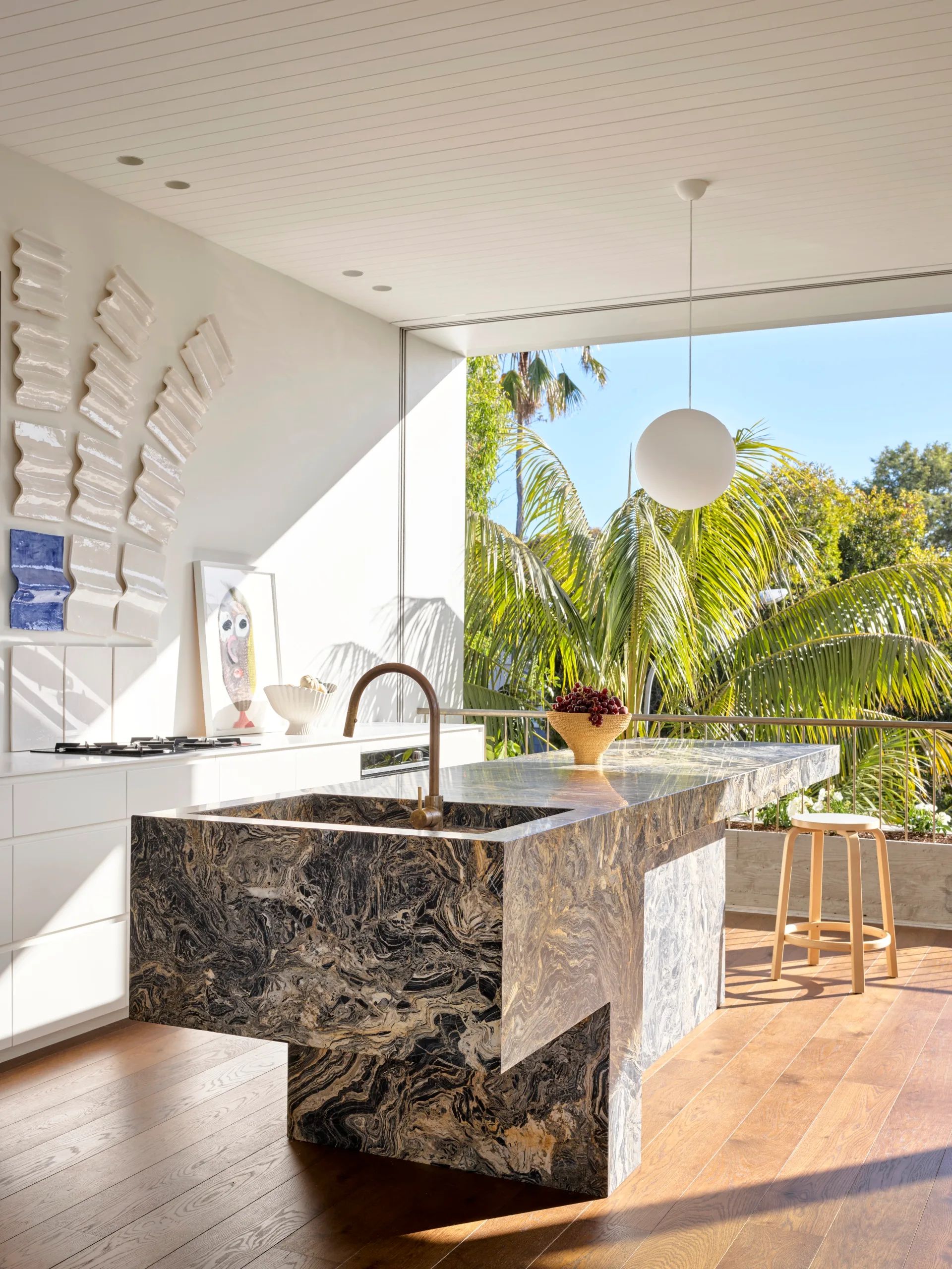 View from Bondi home kitchen with marble island bench and palm trees