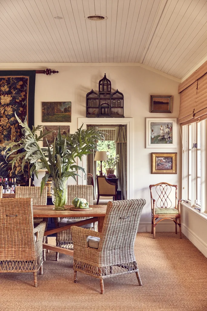 Rattan chairs in a large dining room with a wall tapestry hanging