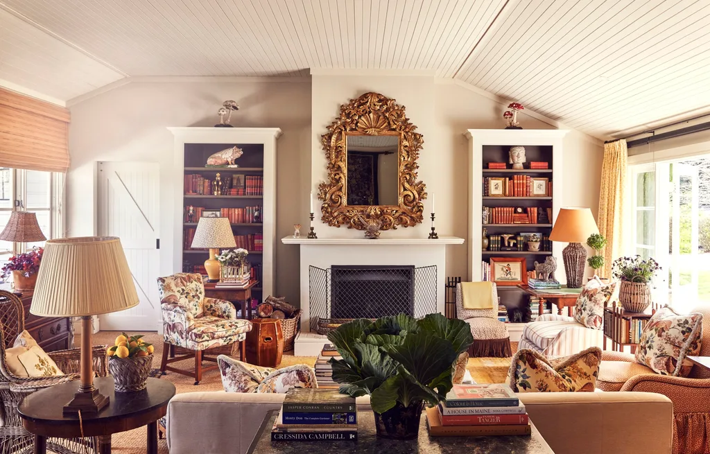 A large colourful and cosy living area centred around a fireplace with a gilded mirror hanging above