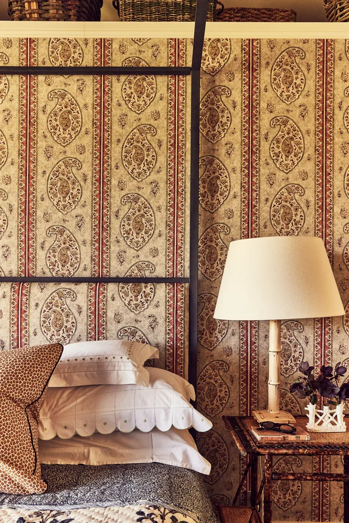 Close-up of a bed and beside table set against paisley wallpaper