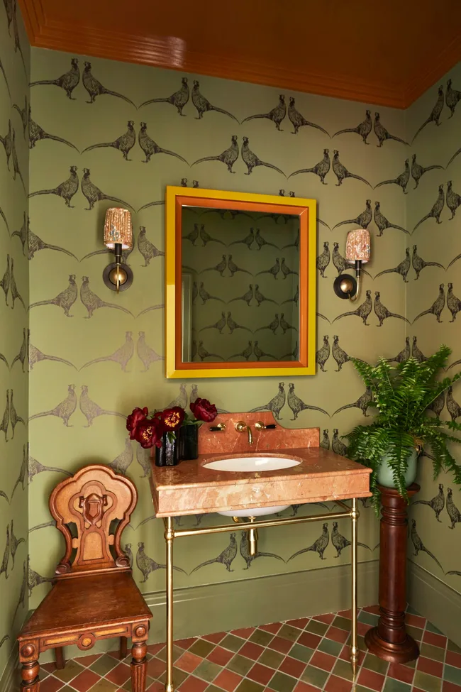 A pink marble bathroom sink in a wallpapered bathroom