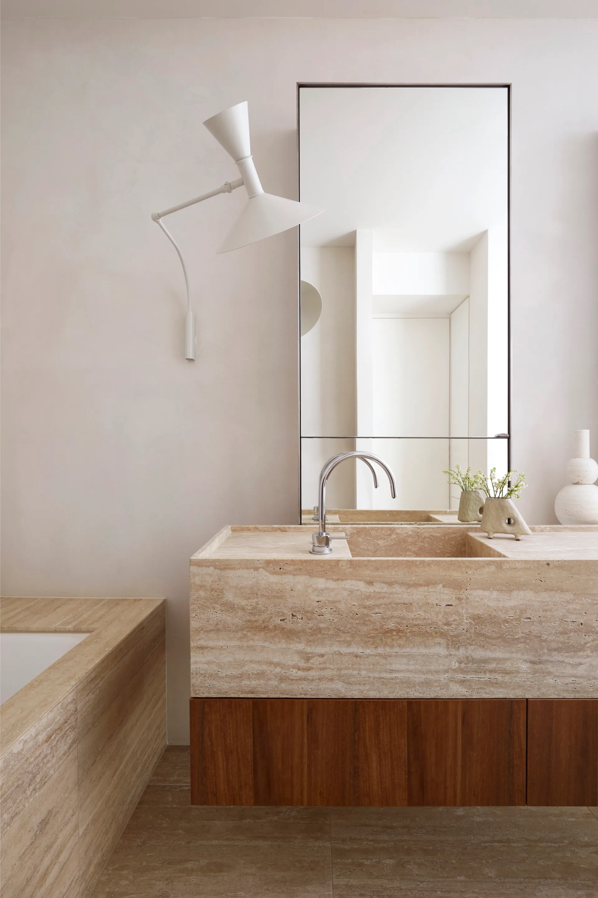 A marble and timber-toned bathroom with a built-in sink and square bath tub