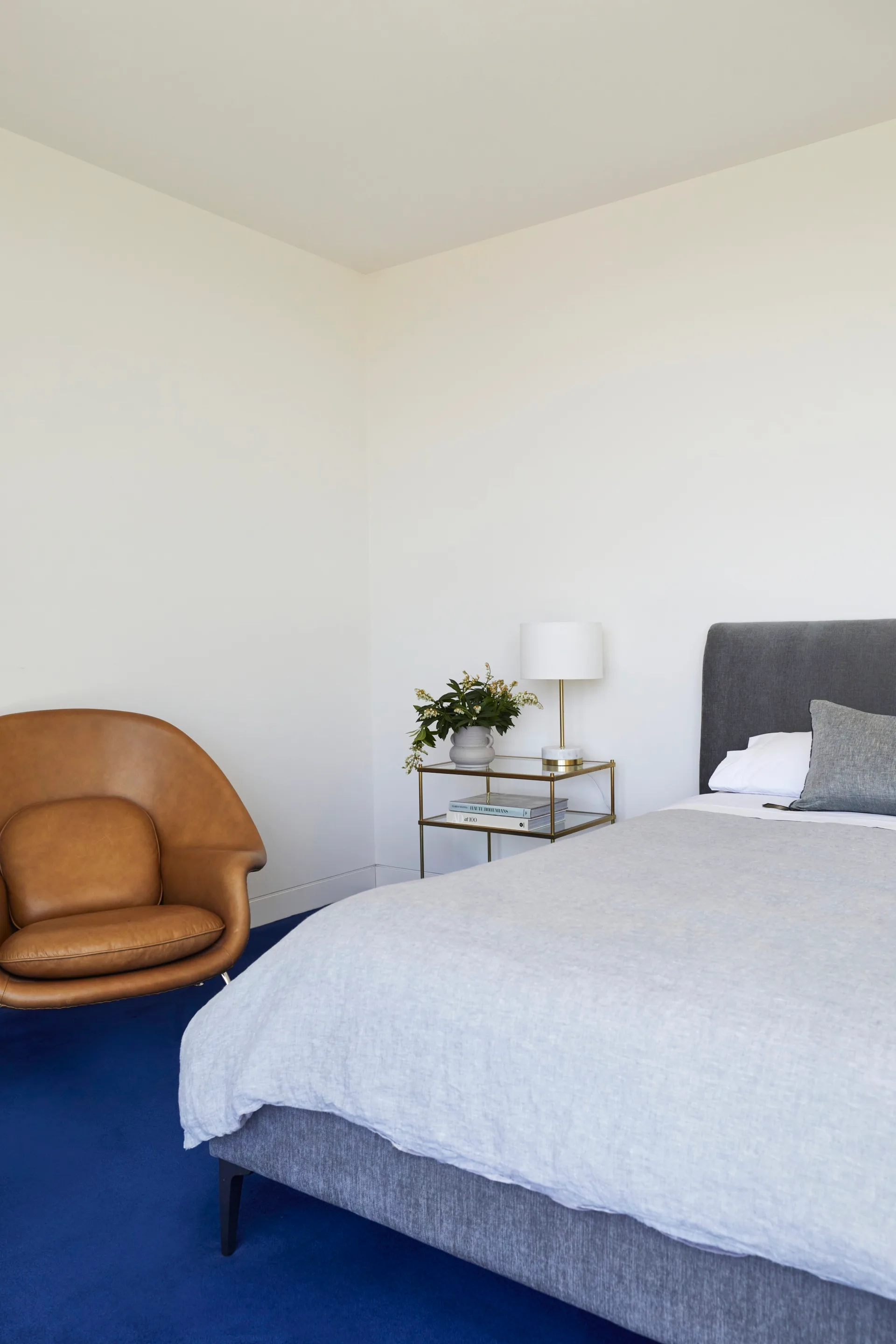 Bedroom with blue carpet and a leather armchair