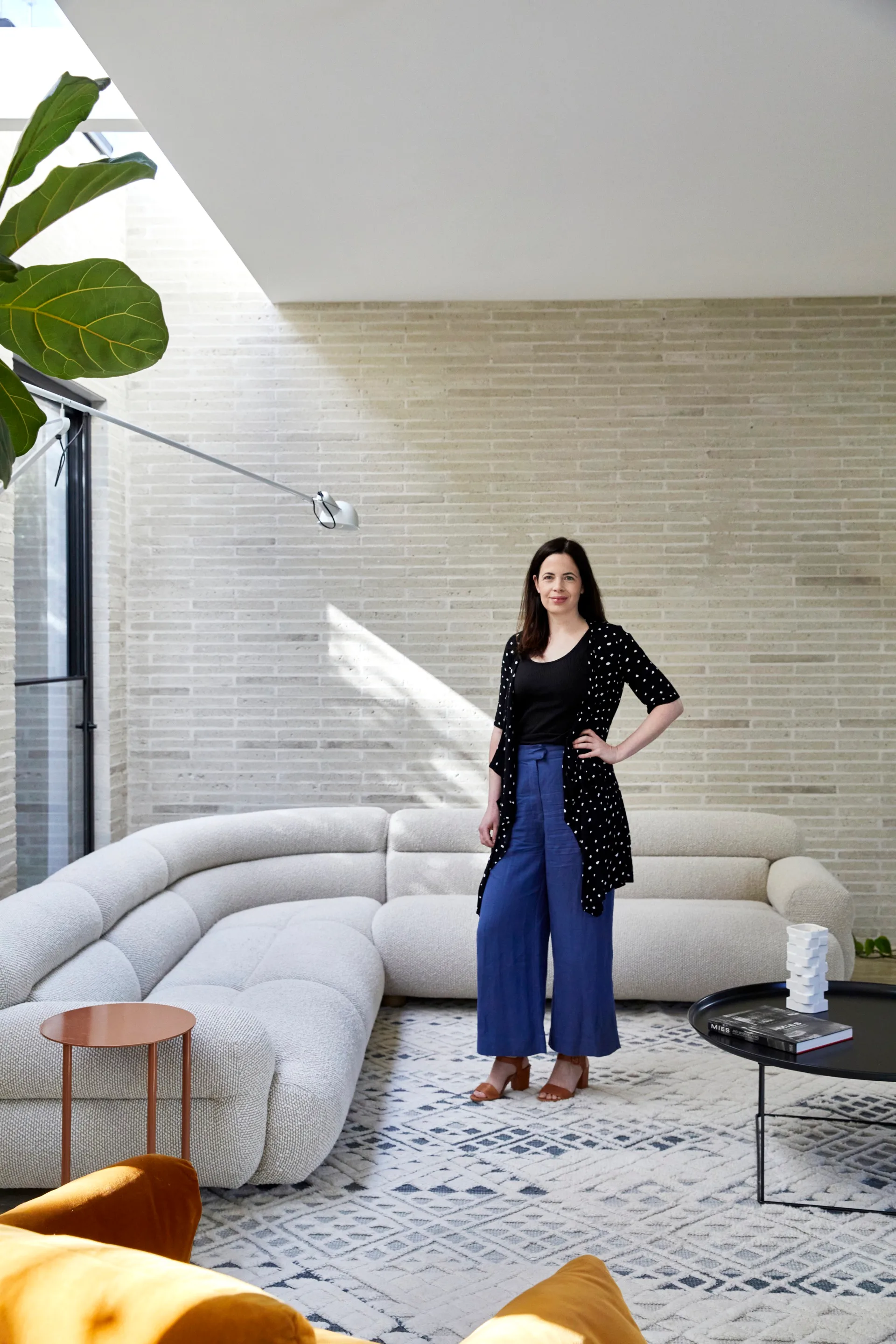 Anna Rozen, an architect standing in her complete residential project beside an L-shaped lounge