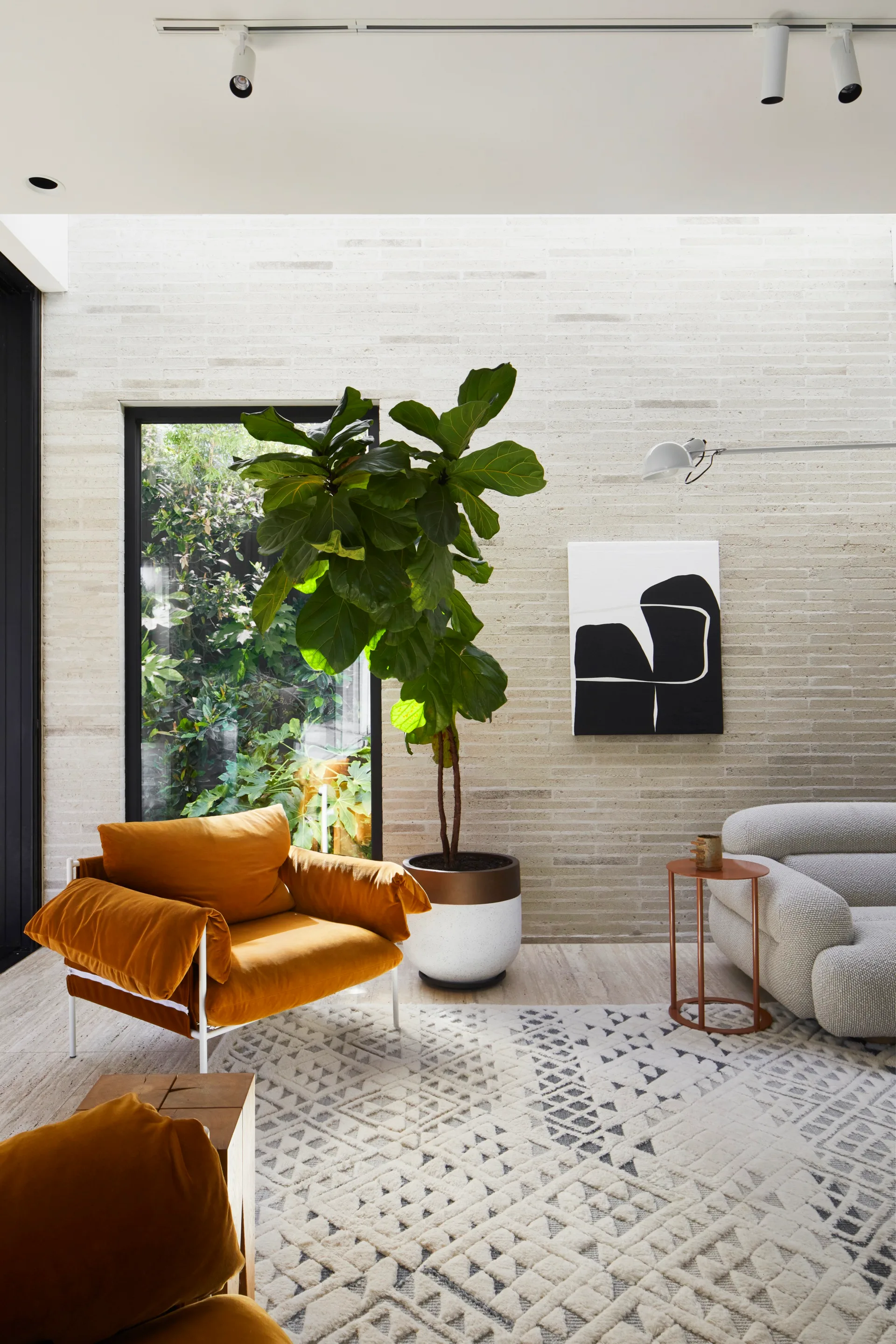 Orange armchair next to a fiddle leaf plant in a lounge area