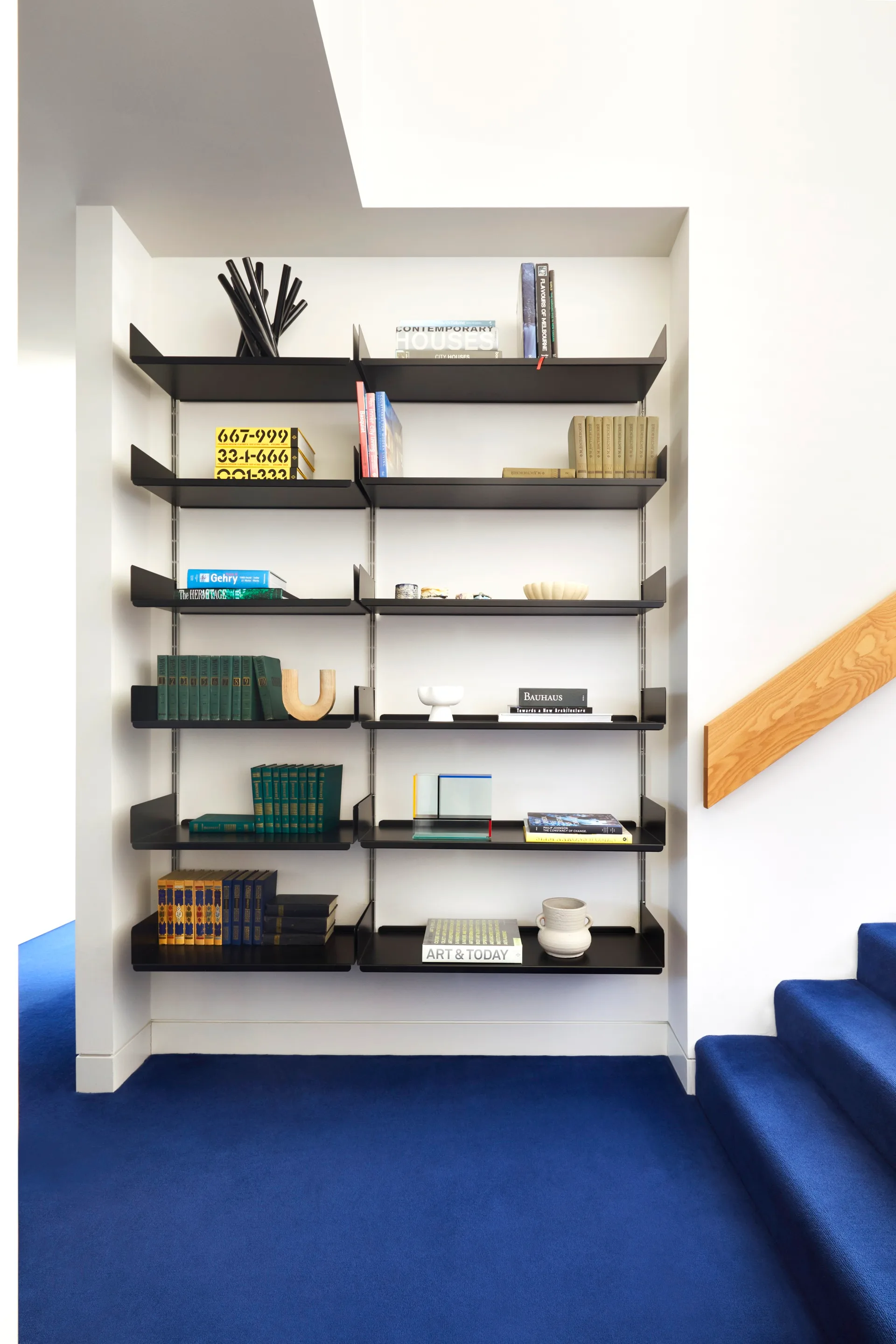 Built-in shelving holding books and trinkets in a space with blue carpet