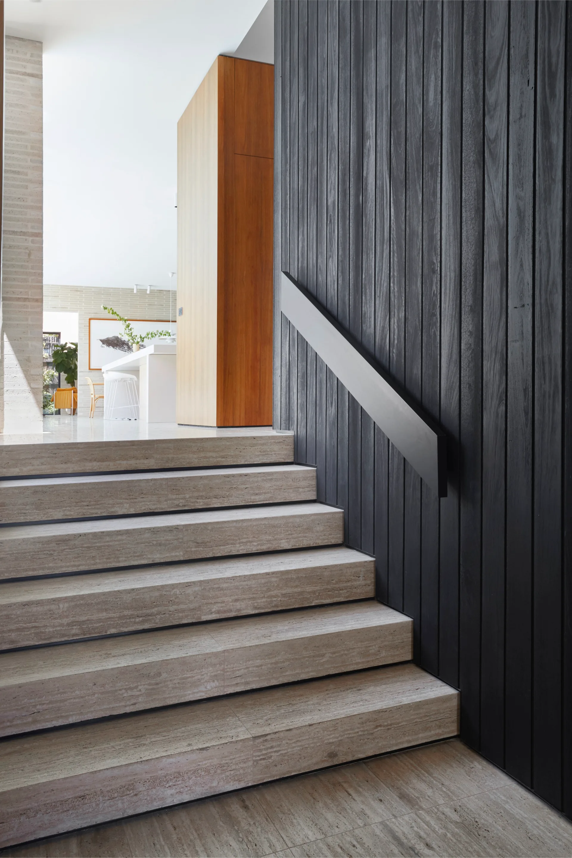 Stairs leading up to the kitchen with a dark timber feature wall
