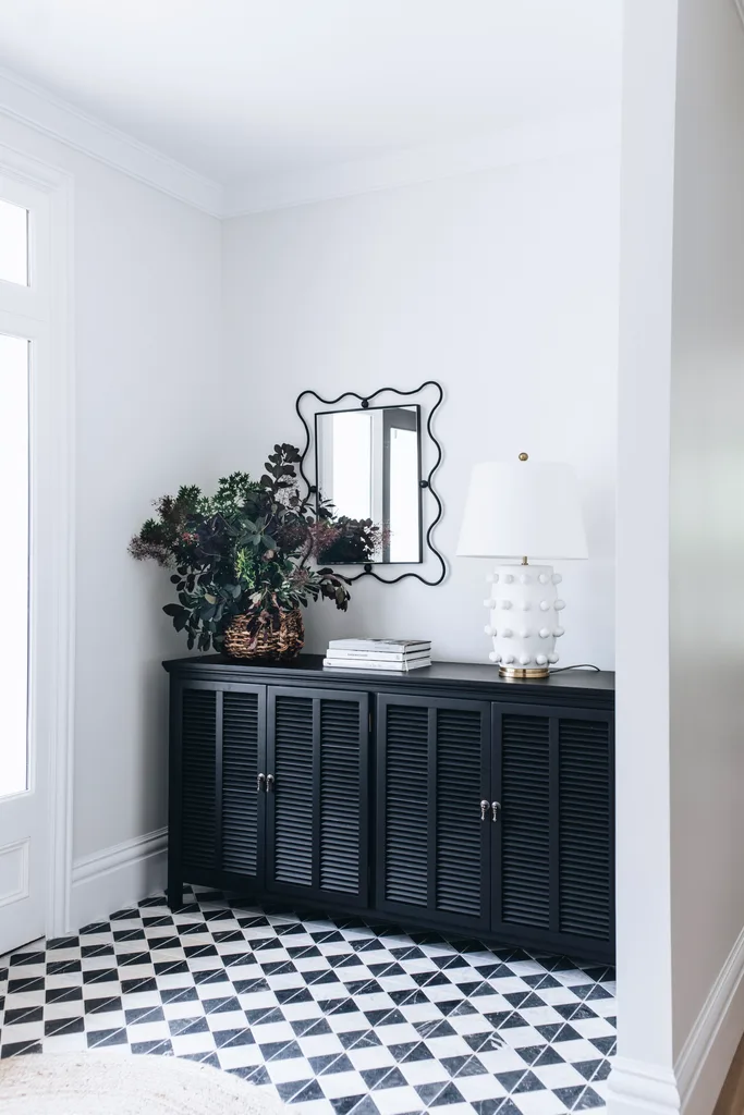 Black timber cabinetry beneath a squiggly mirror