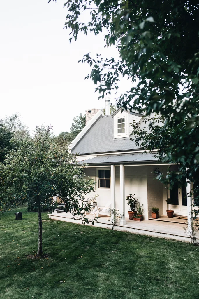 White exterior of the house surrounded by lush lawn and trees