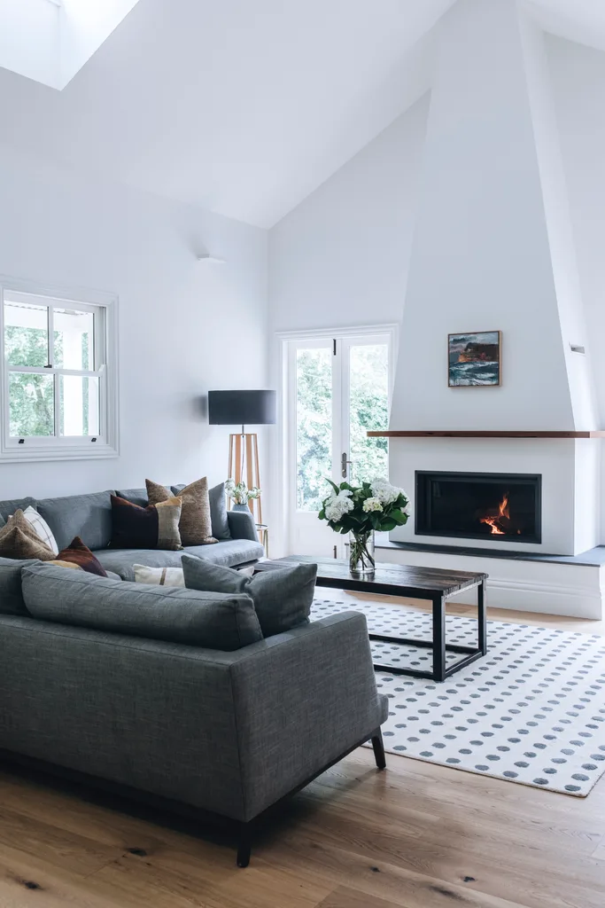 Living area with lots of light and white walls, centred around a burning fireplace