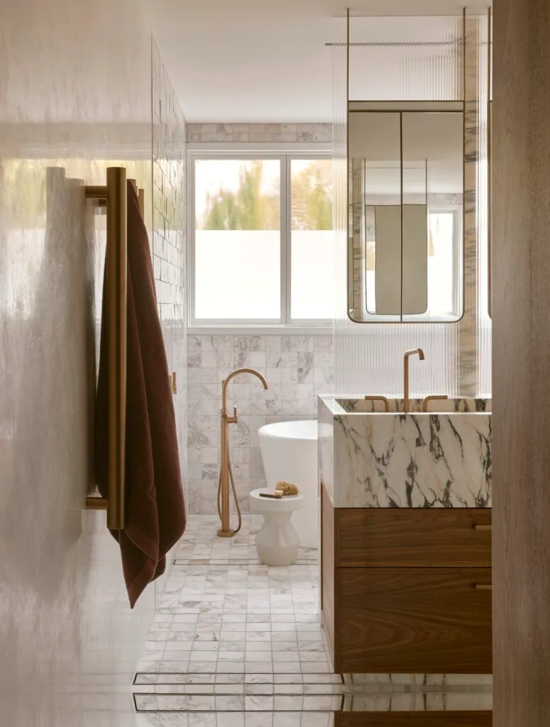 A marble, timber and tiled bathroom with brass fittings