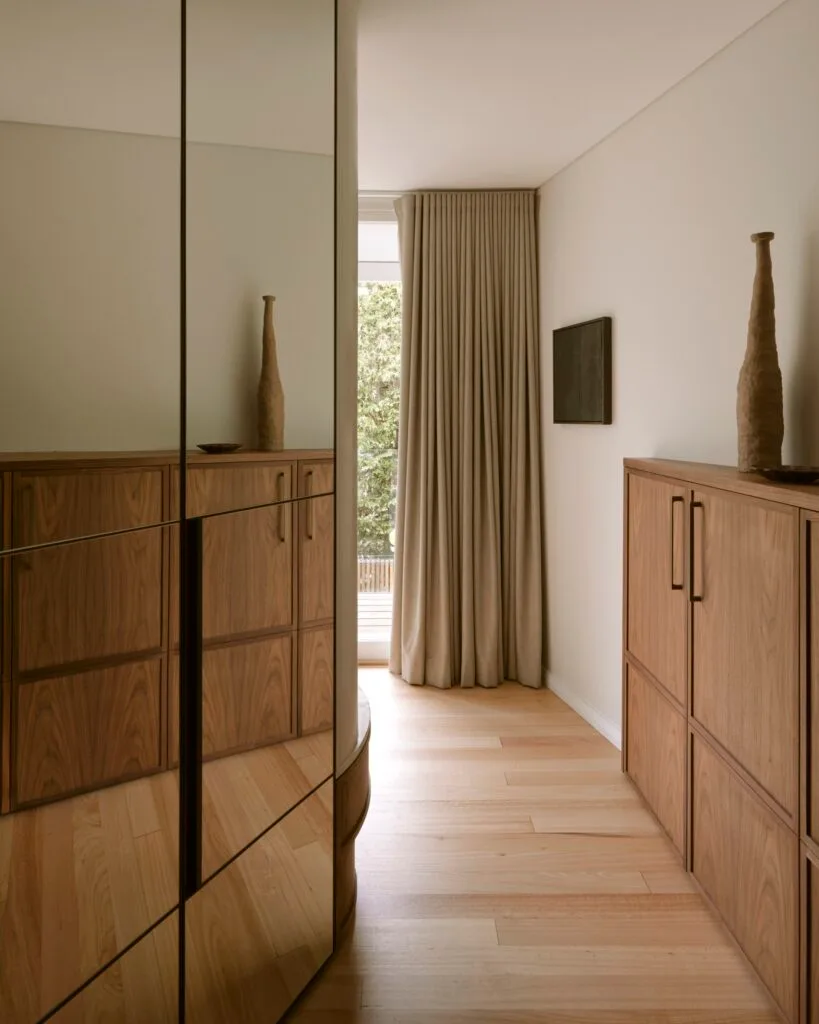 A mirrored wardrobe leading to a neutral-toned bedroom