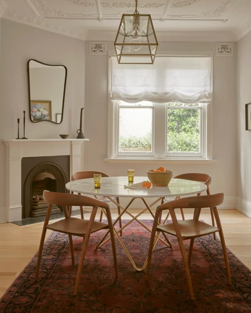 Contemporary dining room with a marble dining table, timber dining chairs and a red rug