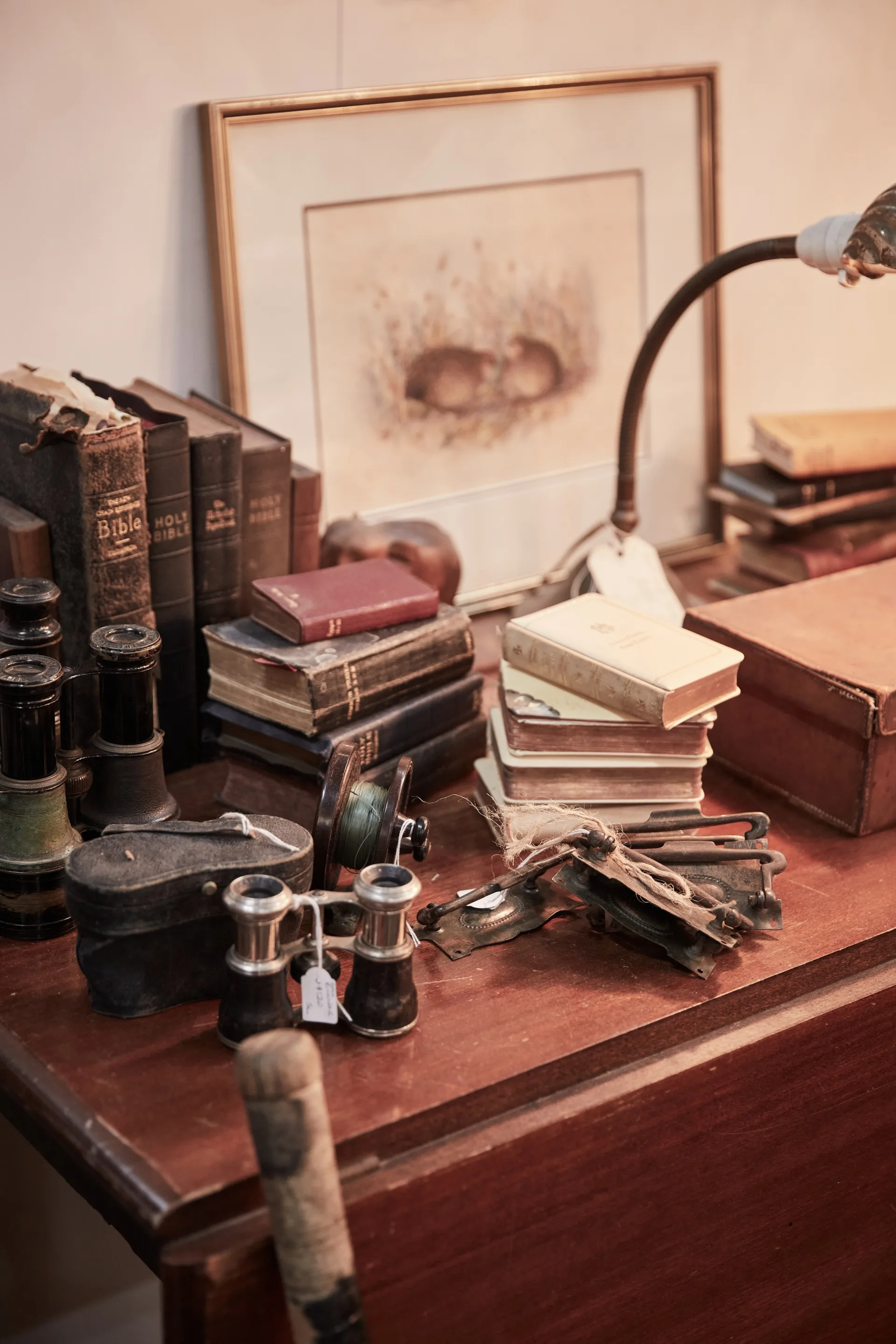 Old books stacked on a timber desk next to some old trinkets