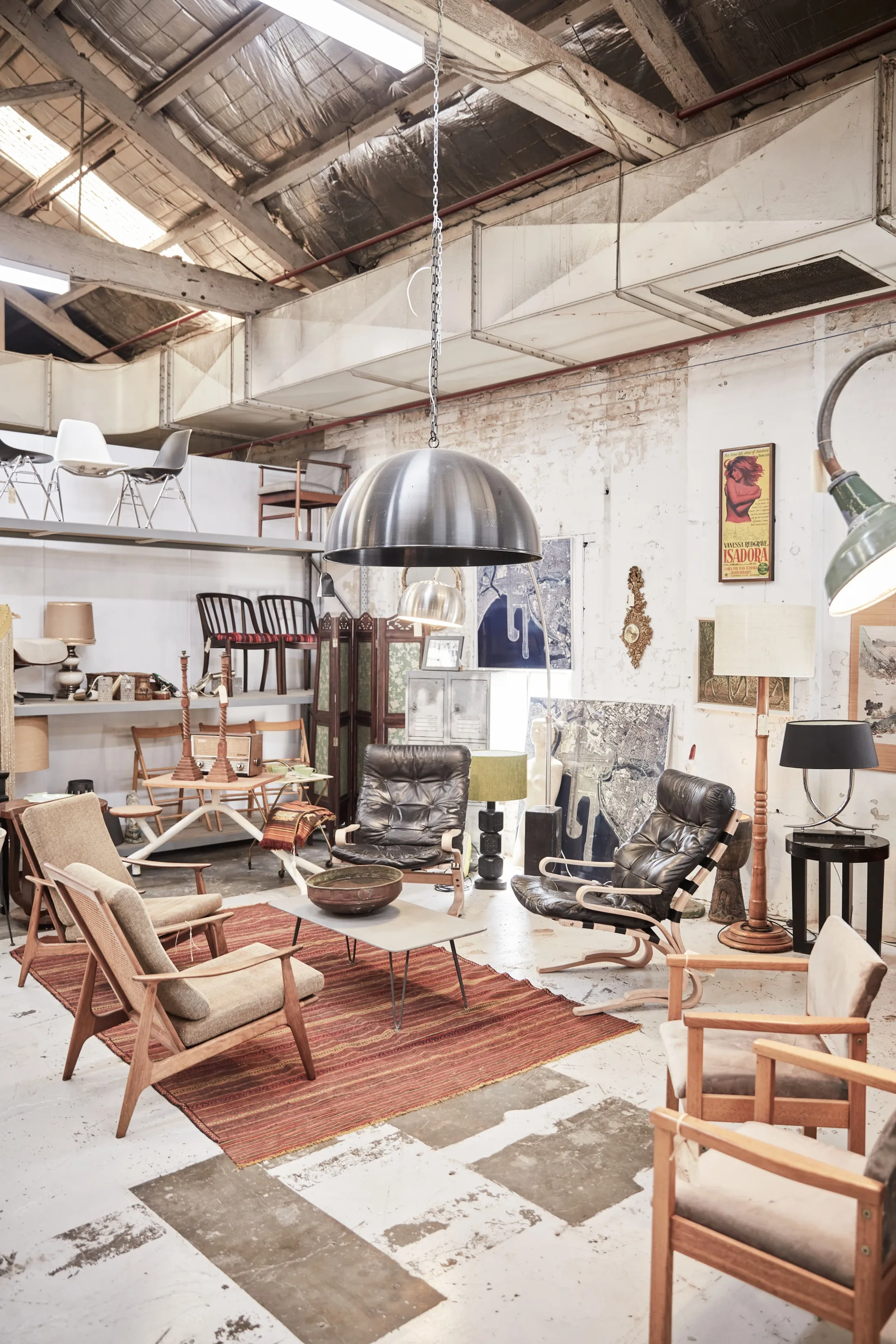 A display of retro armchairs below a large silver pendant light