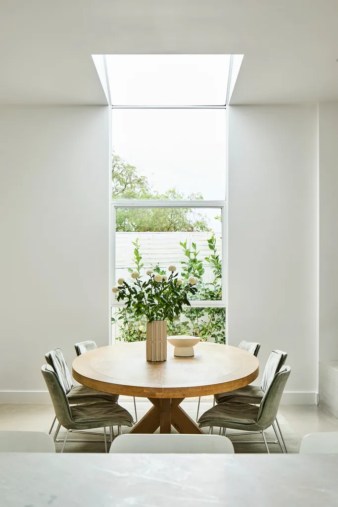 circular timber dining table under a skylight