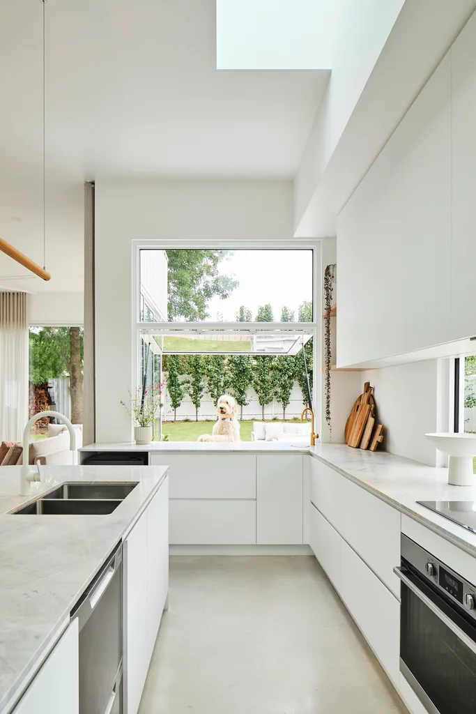 all white kitchen with a servery window leading out to a deck