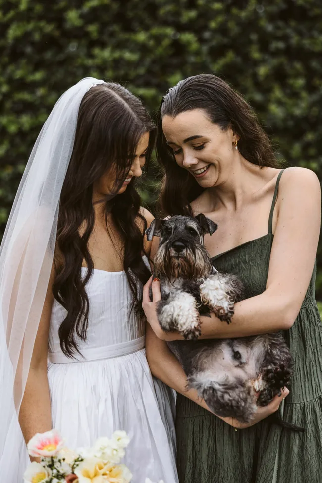 Lucy and her sister Isobel smiling at Lucy's dog, Arlo